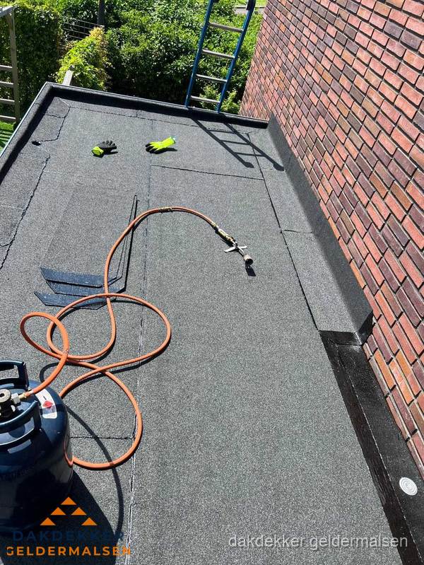 Plat dak met bitumen en brandgereedschap van dakdekkersbedrijf in Geldermalsen