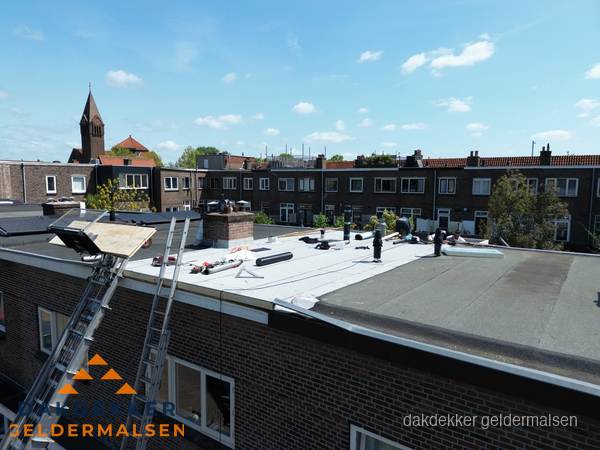 Dakdekkers aan het werk op plat dak in Geldermalsen