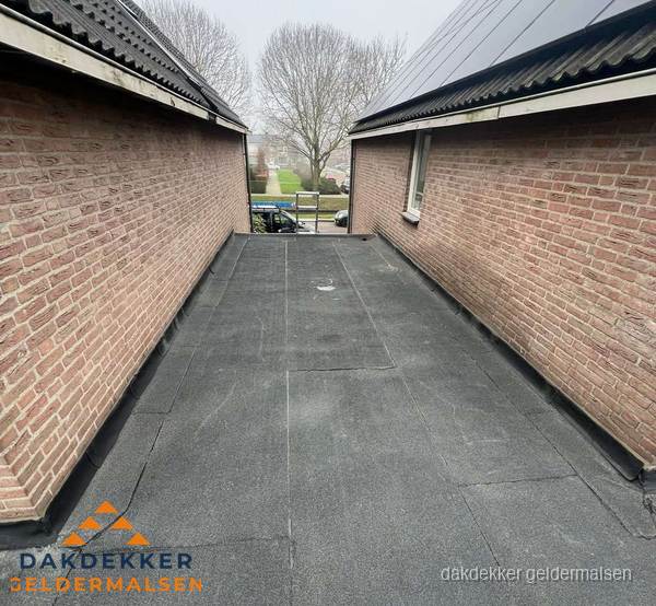 Plat dak met bitumen dakbedekking tussen bakstenen muren in Geldermalsen Plat dak met bitumen dakbedekking tussen bakstenen muren in Geldermalsen