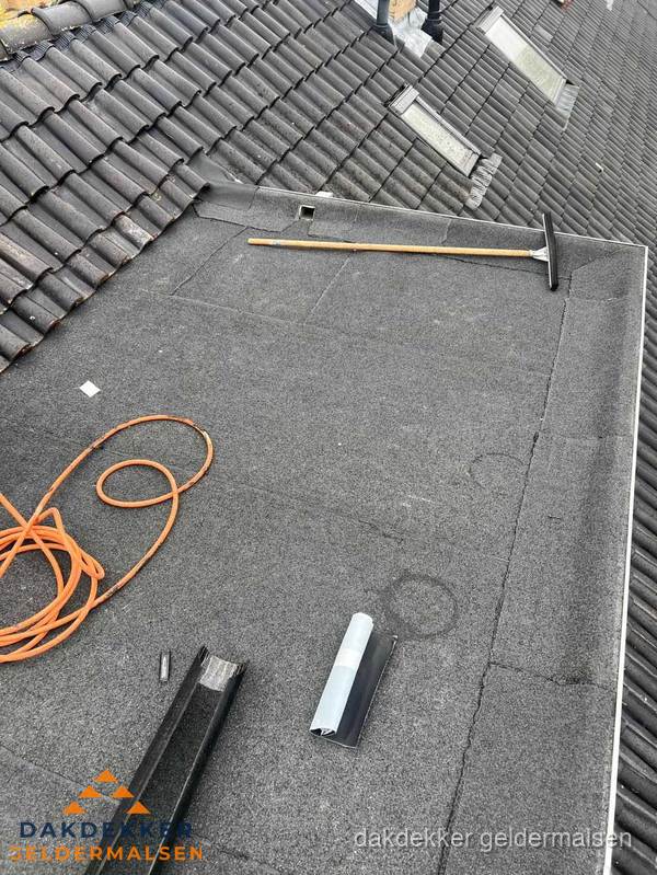Plat dak reparatie met gereedschap en loodstroken in Geldermalsen