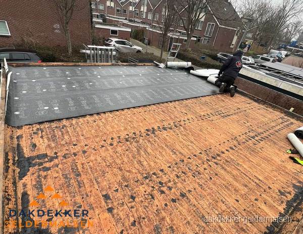 Dakdekker legt onderlaag op plat dak met houten constructie in Geldermalsen