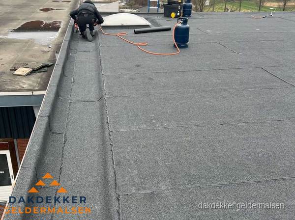 Dakdekker repareert bitumen dakbedekking op groot plat dak in Geldermalsen