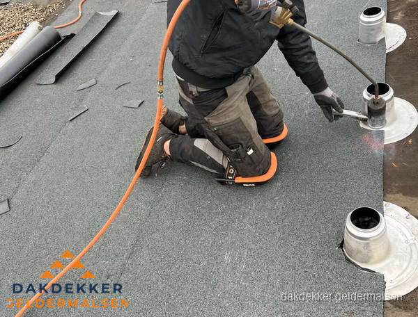 Dakdekker repareert bitumen dakleer bij dakdoorvoer in Geldermalsen